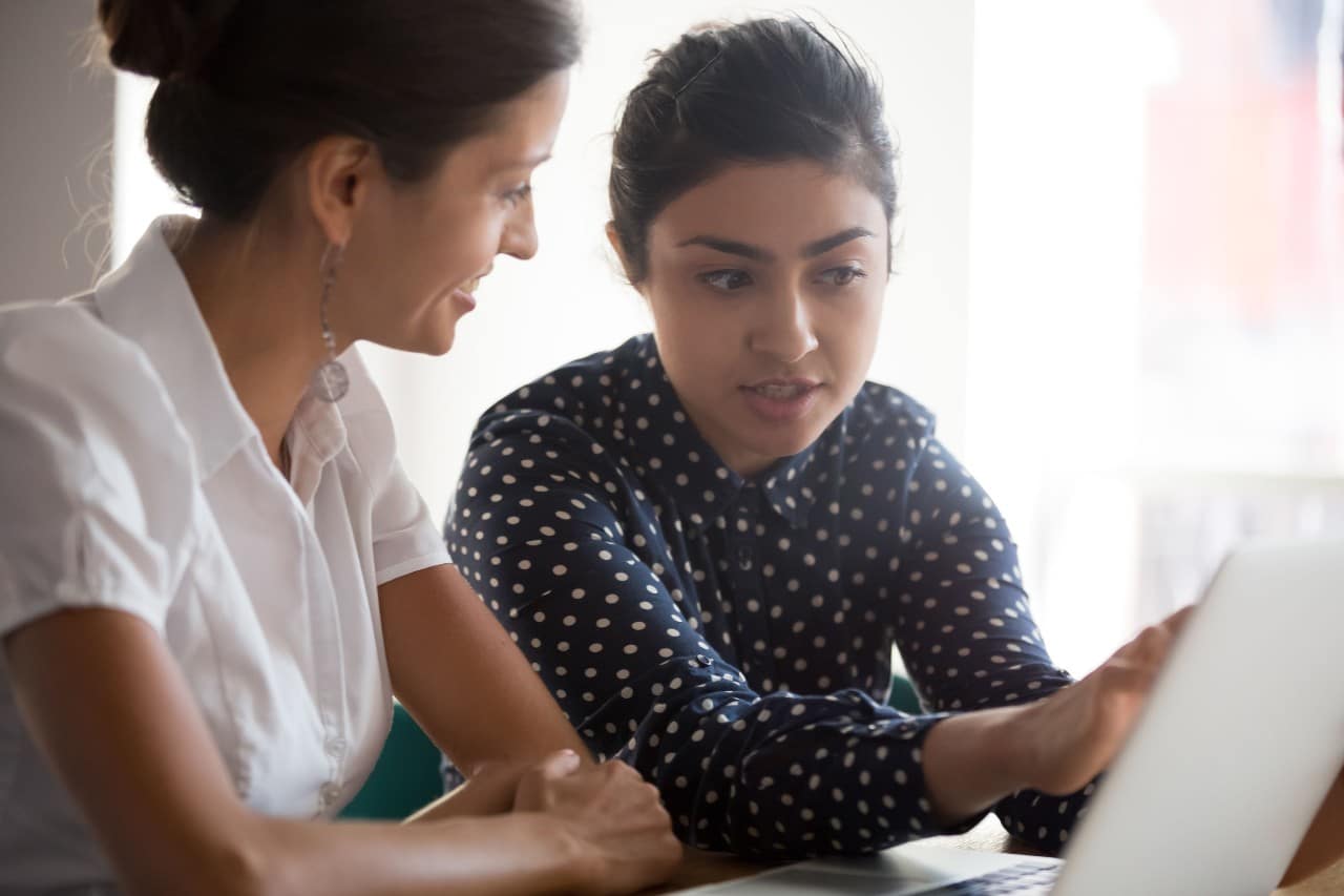 one office worker shows a tablet screen to another; cross-training and upskilling employees concept