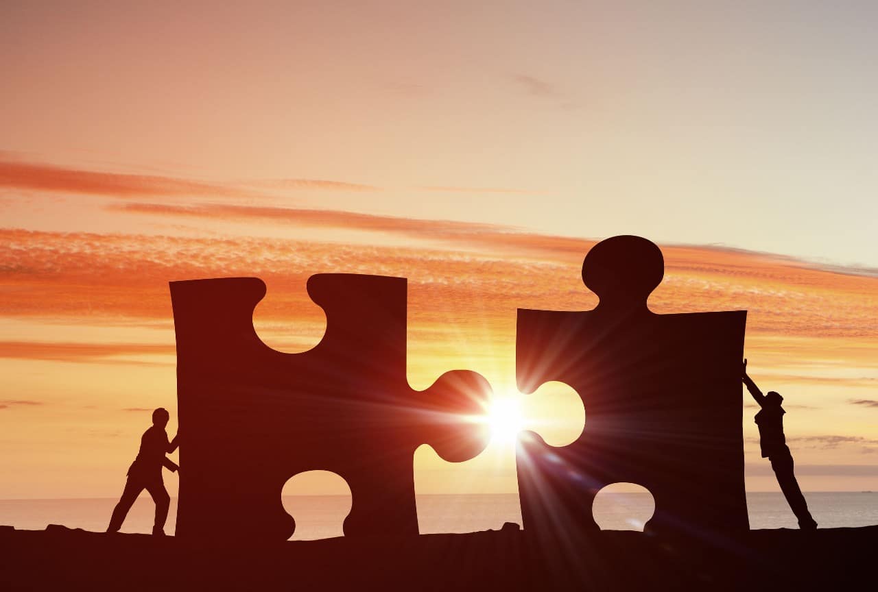 sunrise on two businessperson fitting together giant puzzle pieces; Reskilling and Upskilling concept