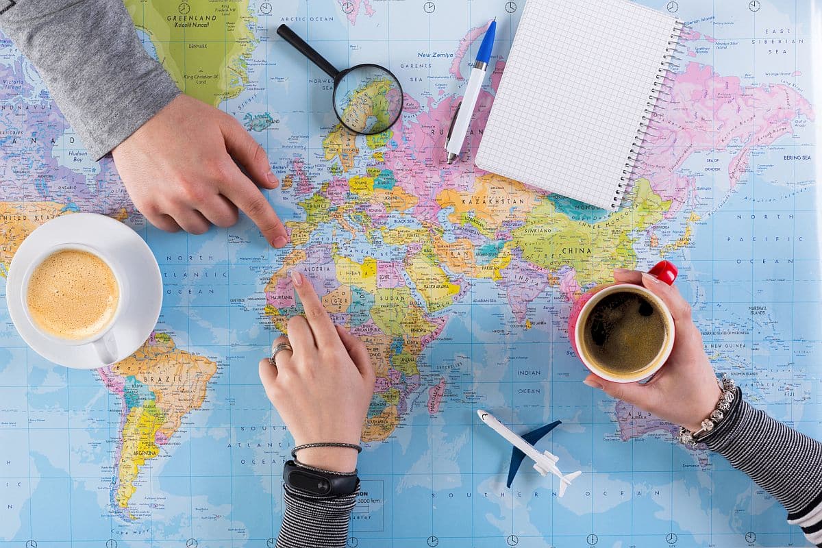 Couple planning airplane trip to Morocco, point on map, taking notes in blank notebook; Predictive analytics concept