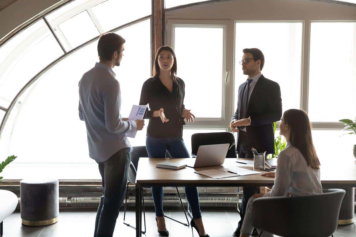business team meets informally standing around a small desk; succession planning and upskilling concept