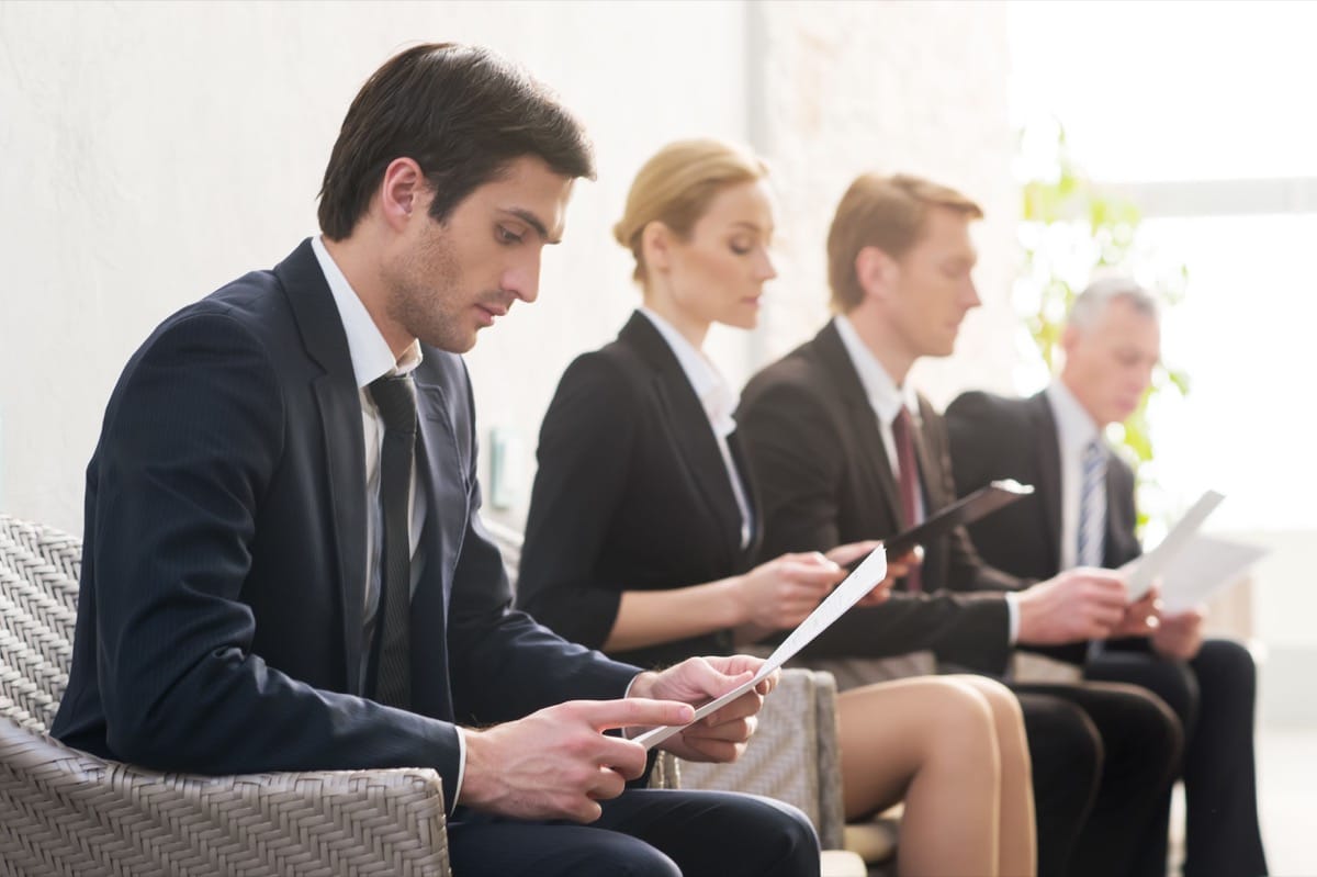 Job candidates. Four people in formalwear waiting in line while sitting at the chairs and holding papers in their hands, representing how to overcome talent shortages