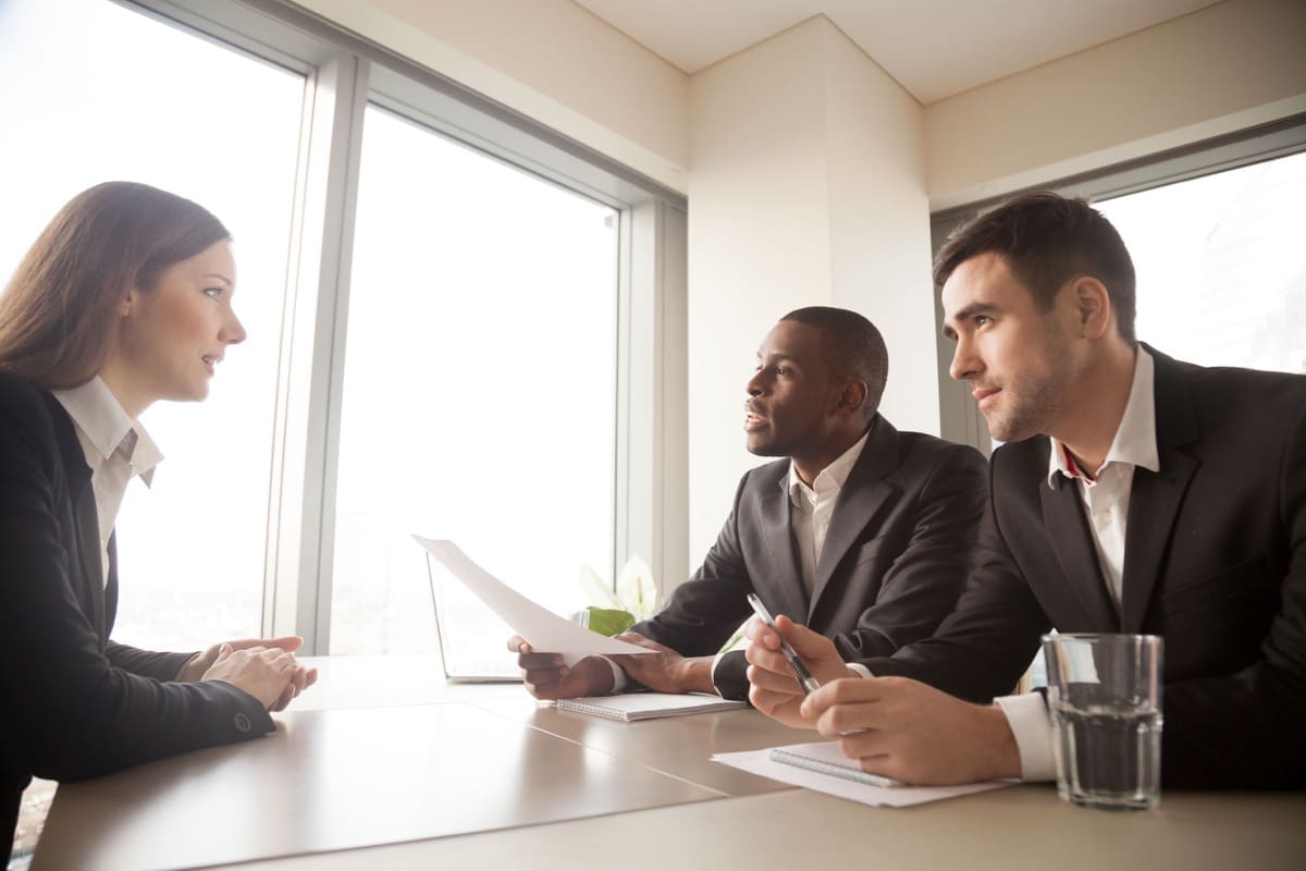 Multinational hiring managers conducting interview with female candidate; talent crisis concept
