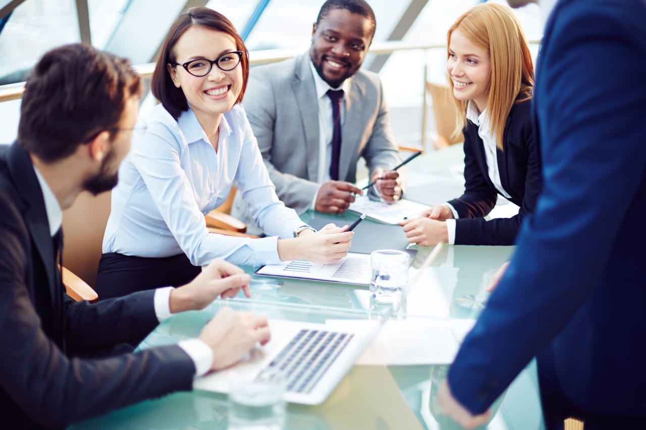 diverse coworkers meet around a laptop, everyone is is smiling; companies hiring veterans concept