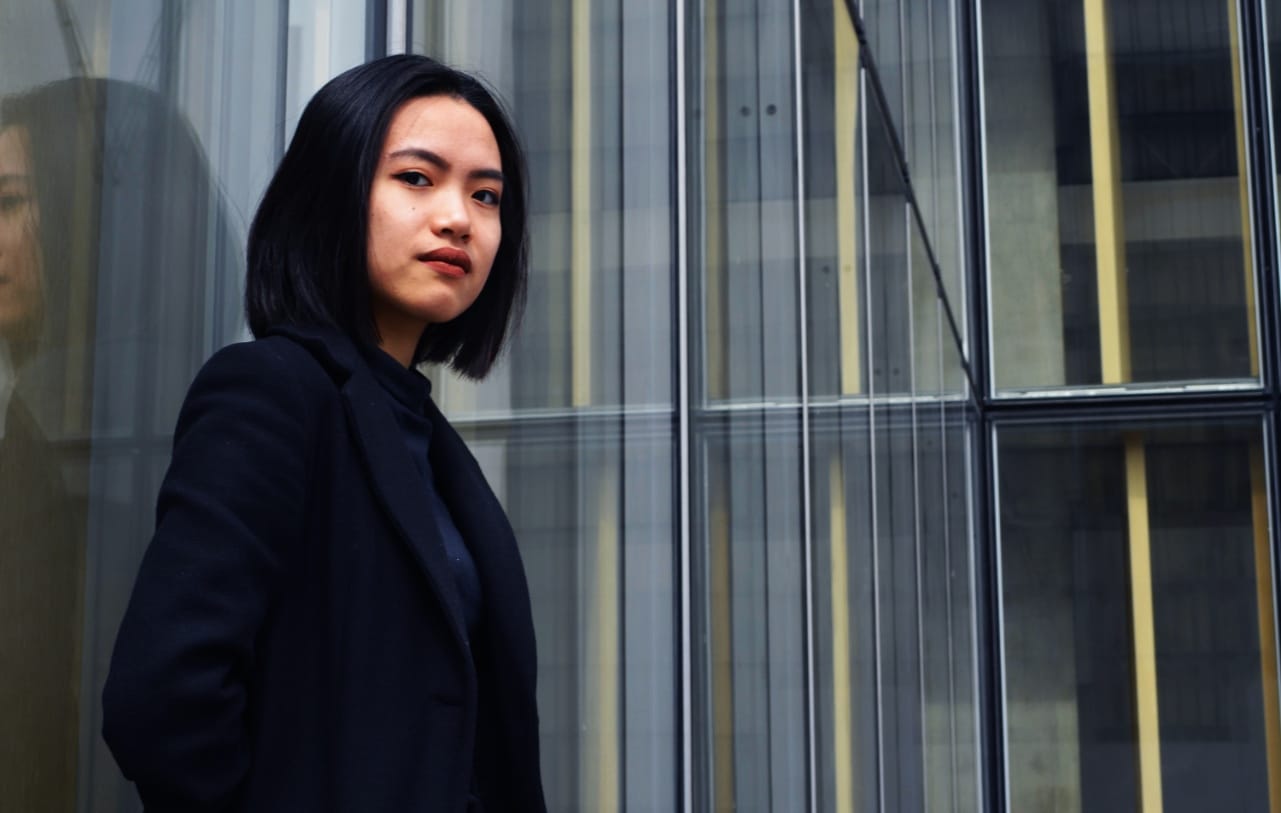 businesswoman stands in front of a glass office building; Talent Management, Finance and COVID concept