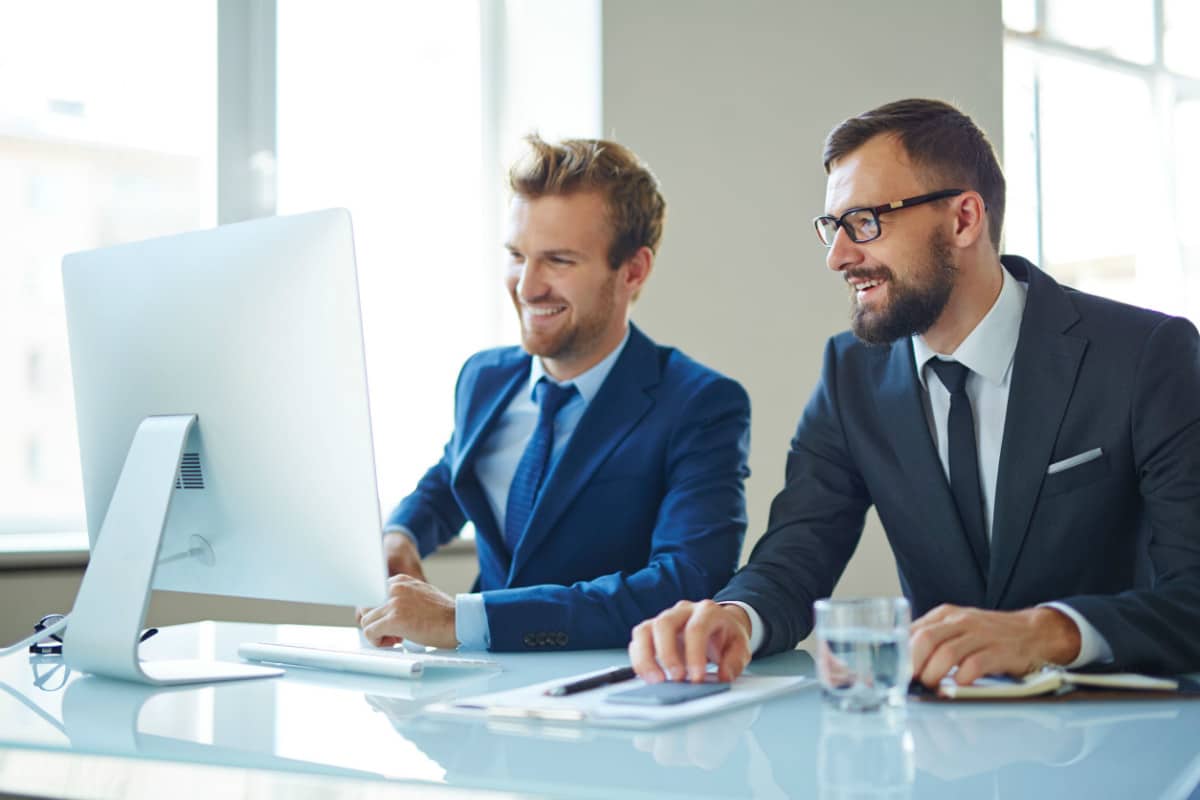 Two young hip businesspersons at a desk looking at the same monitor; employer branding experts concept