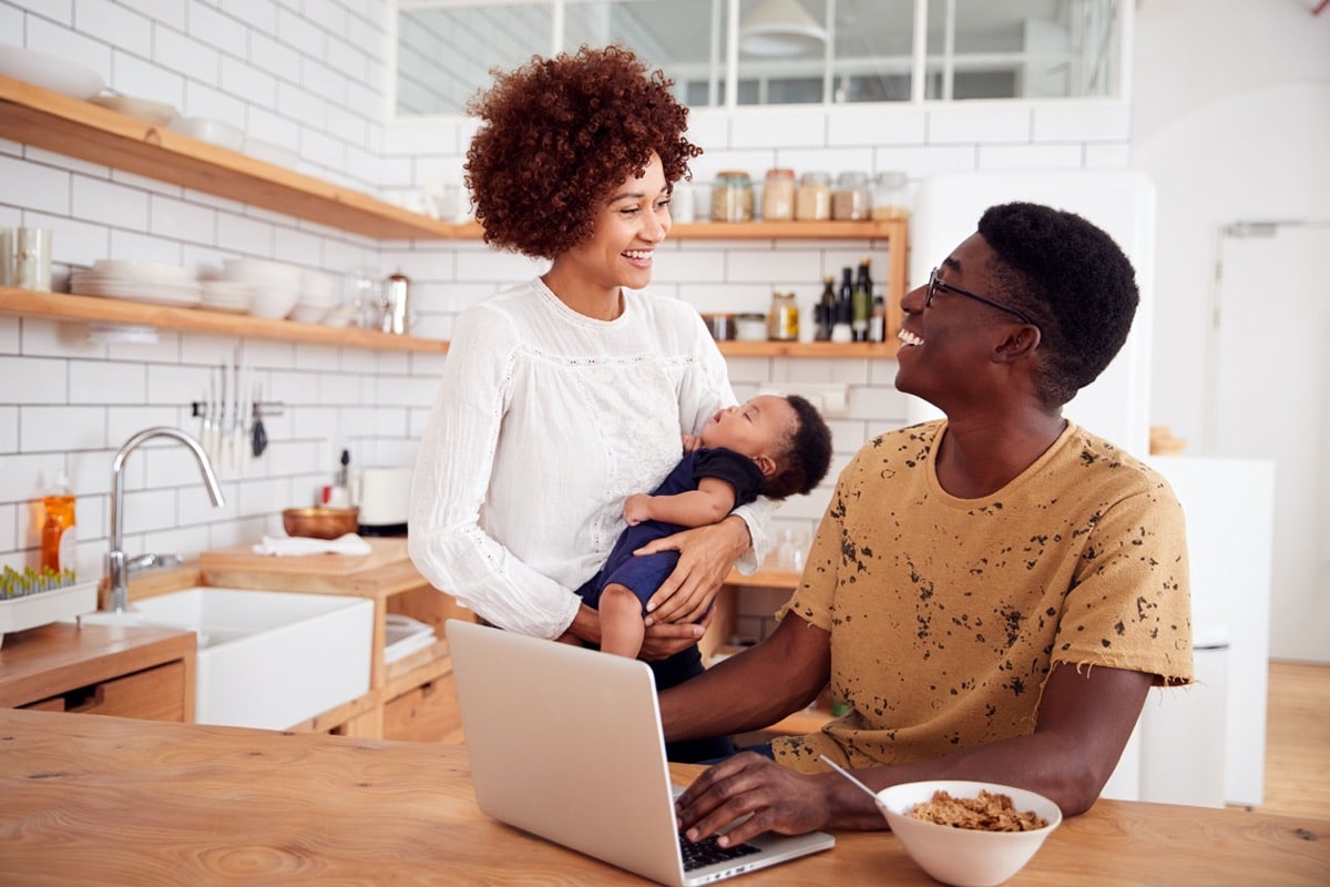 Family in kitchen, father caring for baby; supporting remote employees concept