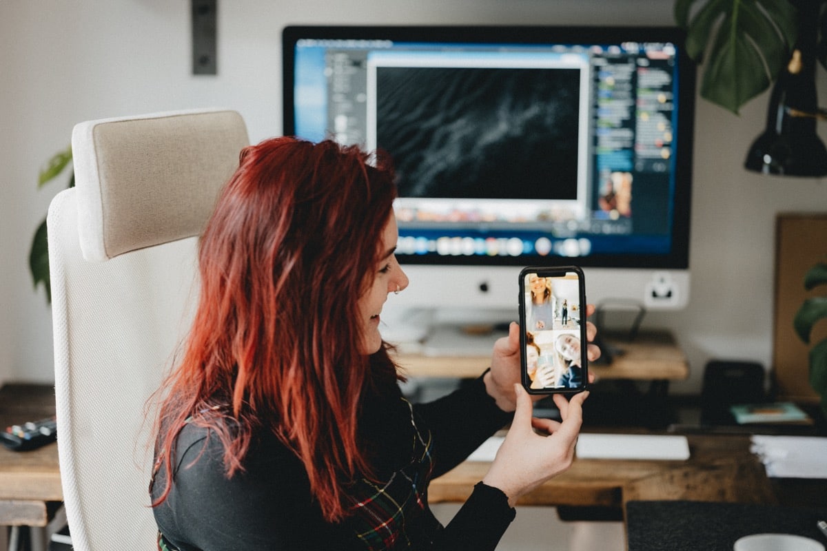 woman using a desktop, laptop and phone in her home office; remote employer brand concept