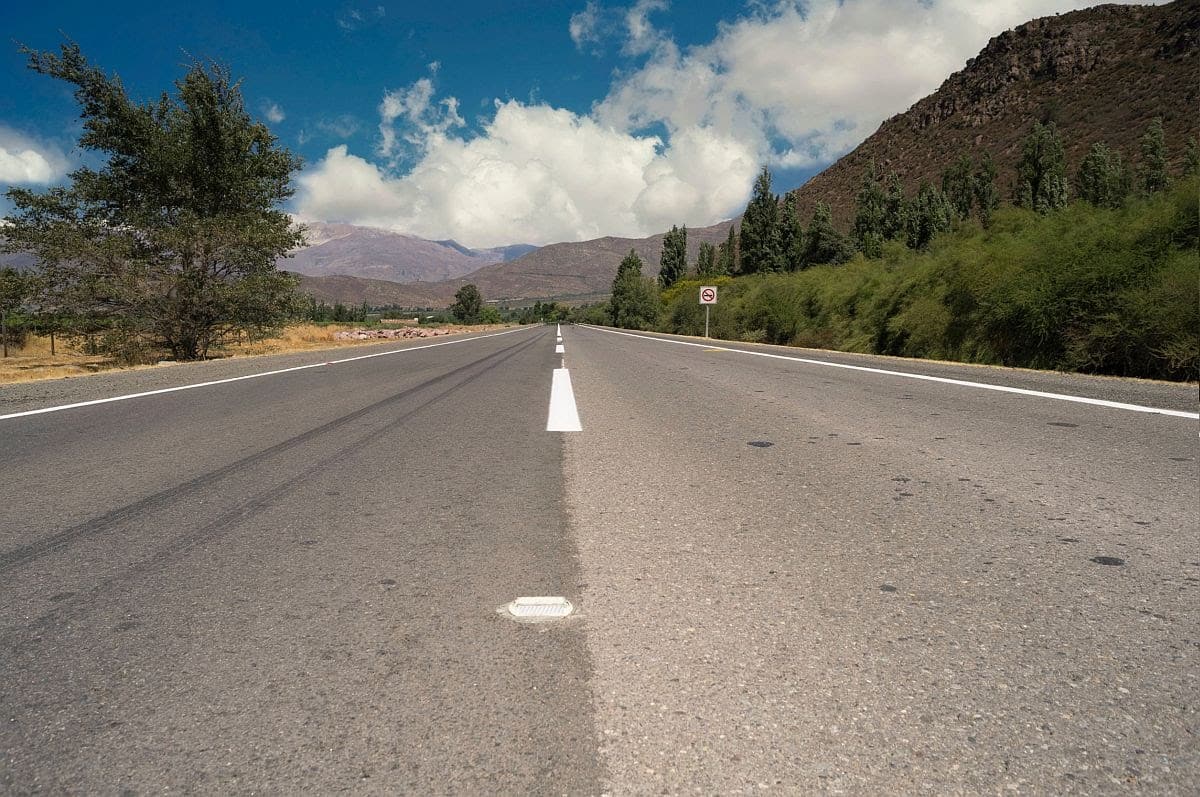 Empty asphalt street on mountain countryside landscape with blue sky background. Logistics transportation road for shipping industry or transport business.