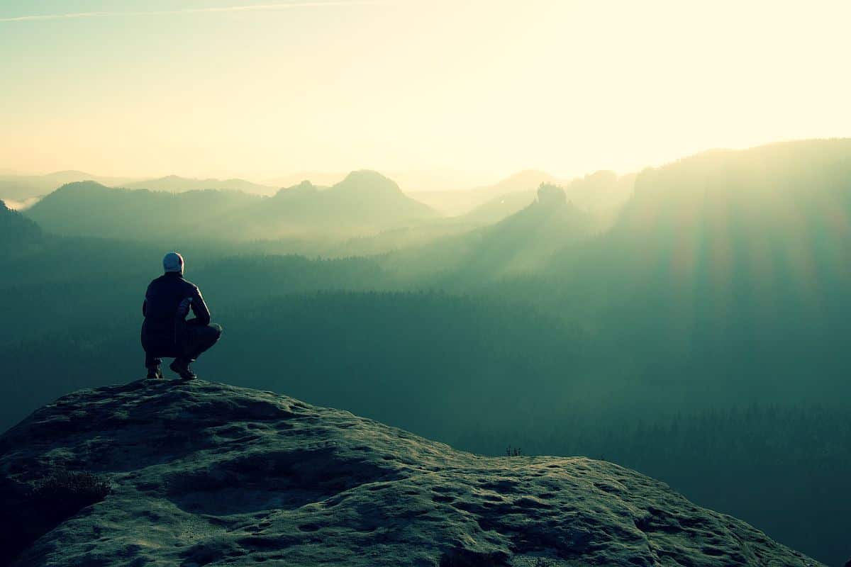 Hiker sits on a rocky peak; lifelong learning concept