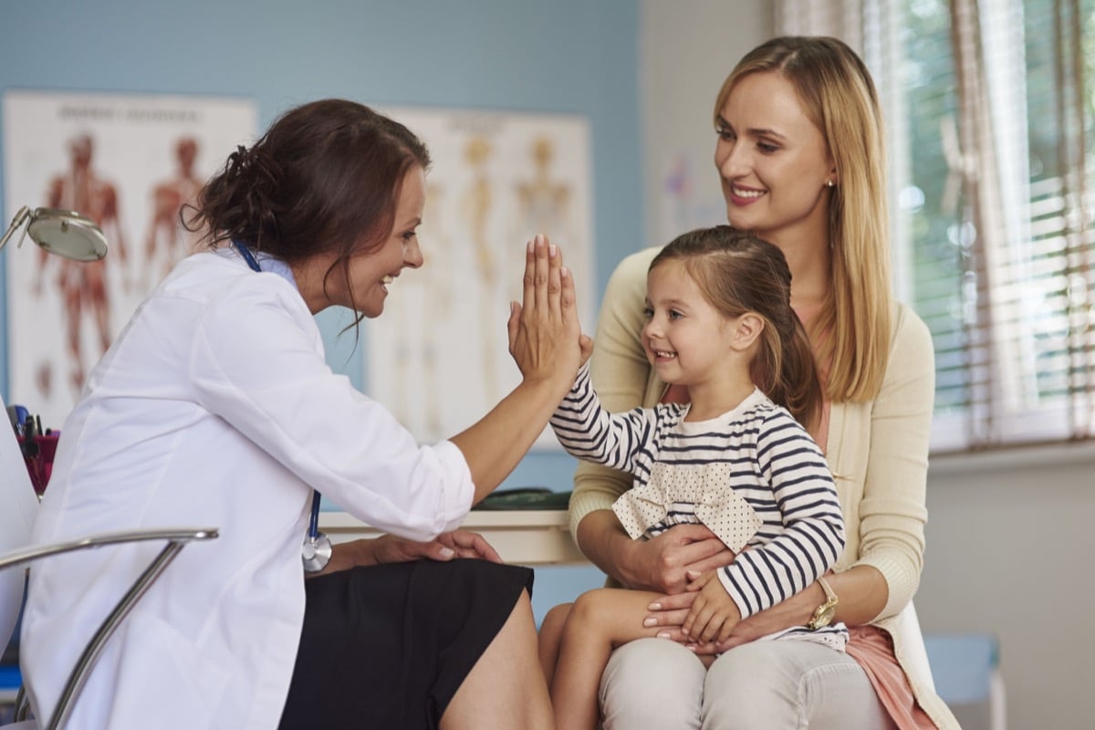 Smiling daughter, mother and doctor in warm doctor's office; representing how healthcare providers can use AI to recruit great doctors