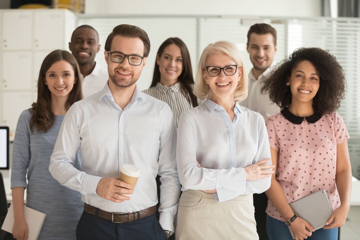 Smiling professional business coaches leaders mentors posing together with diverse office workers; better hiring decisions concept