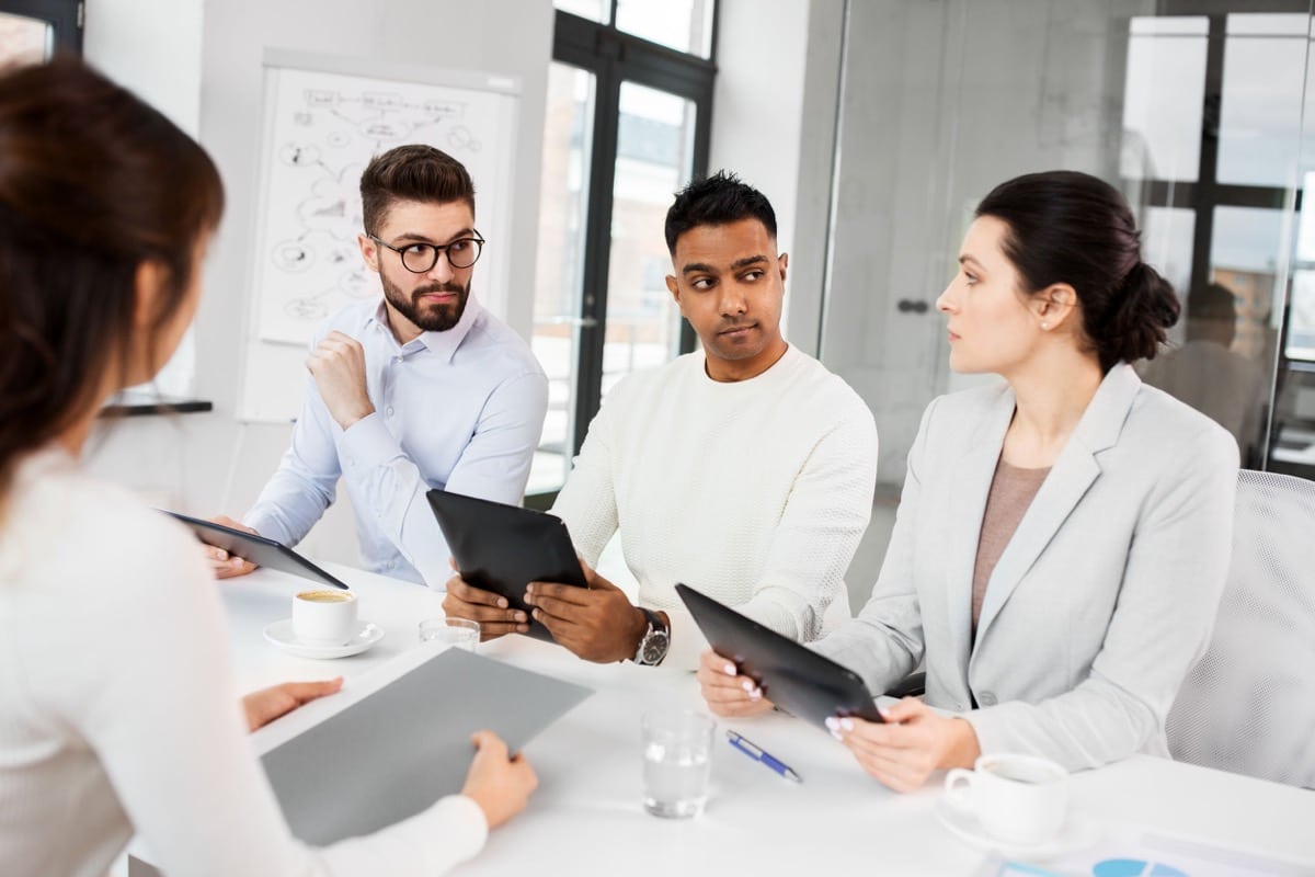 new job, hiring and employment concept - international team of recruiters with tablet computers having interview with female employee at office
