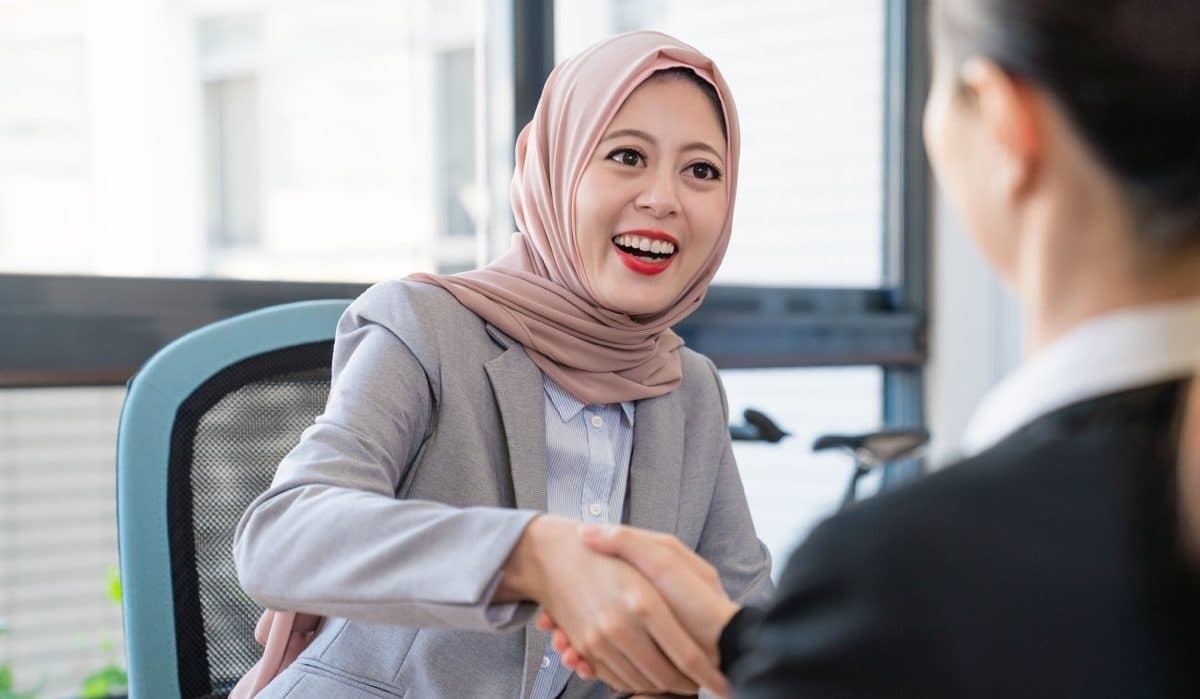 A Muslim young businesswoman is happy about the deal. They shake their hands to celebrate their good partnership.