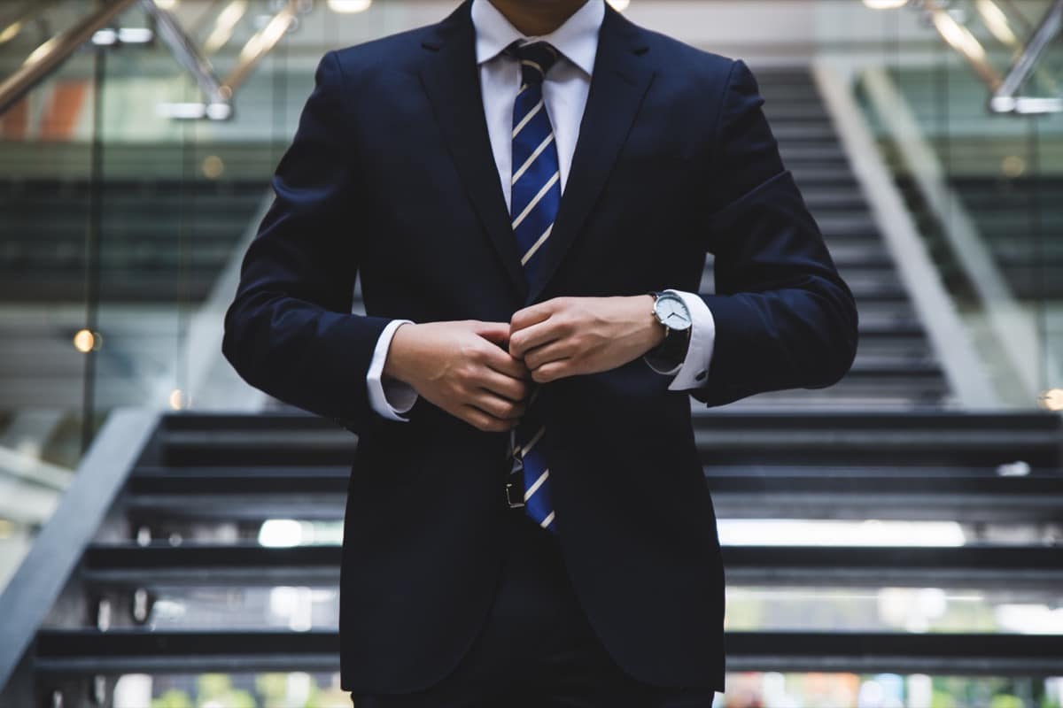 man in tie buttoning his suitcoat; hiring recession concept