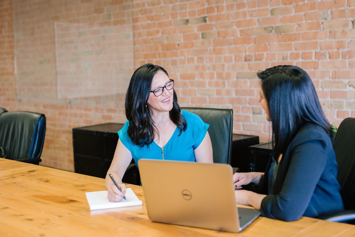 two women conduct a job interview in an office meeting room; veteran employment resources concept