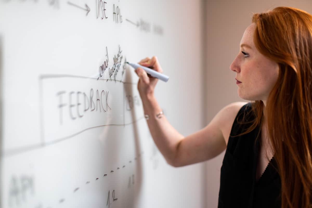 business woman using marker on whiteboard; pandemic impact, dev jobs concept