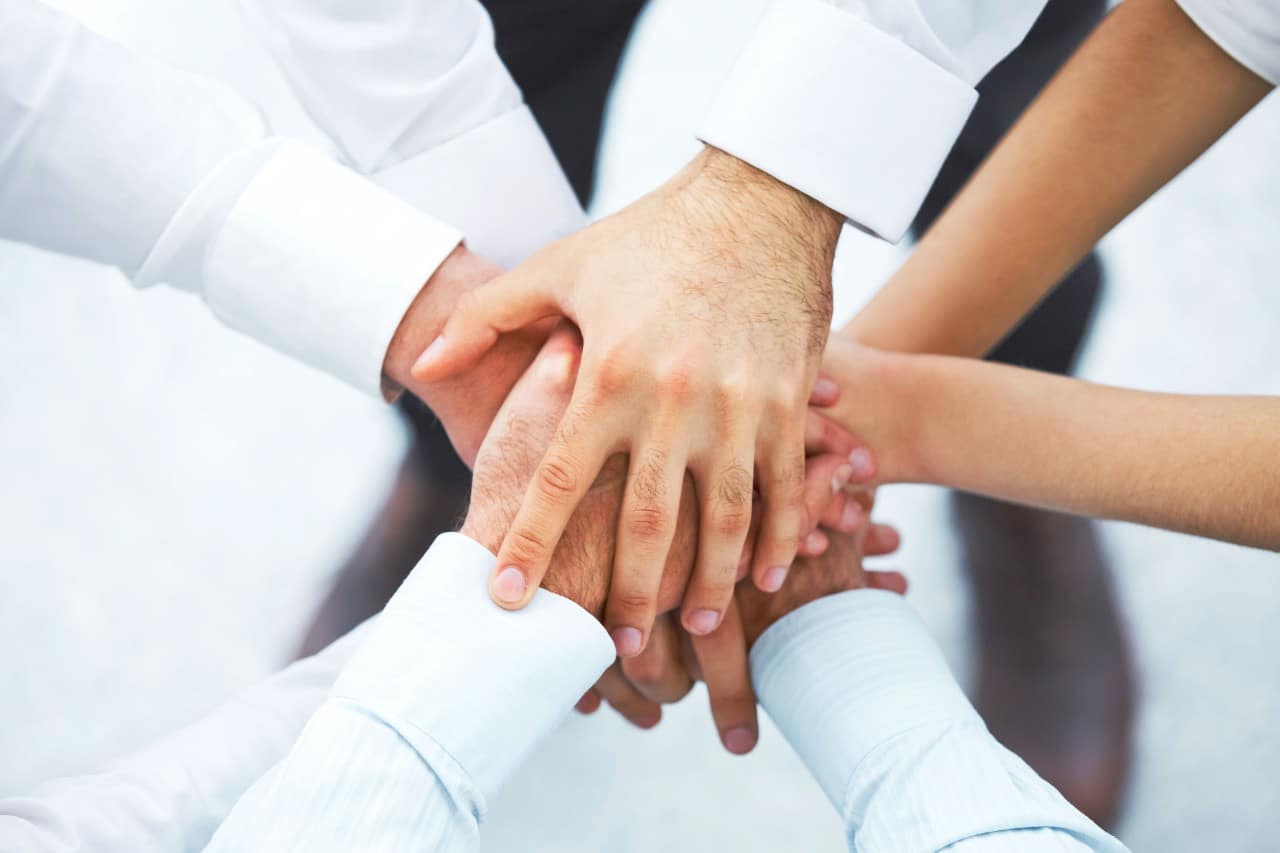 hands of persons of diverse racial background are clasped together; helping furloughed workers concept