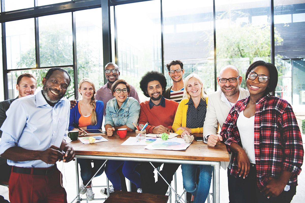 large group of multi-ethnic and multi-generational coworkers smile for camera; successful DEI implementation concept