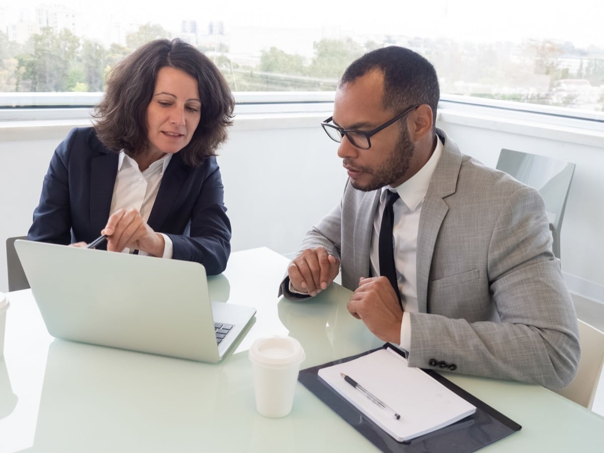 Focused coworkers using laptop. Professionals sitting at table and working with laptop computer in office. Online employer Brand concept