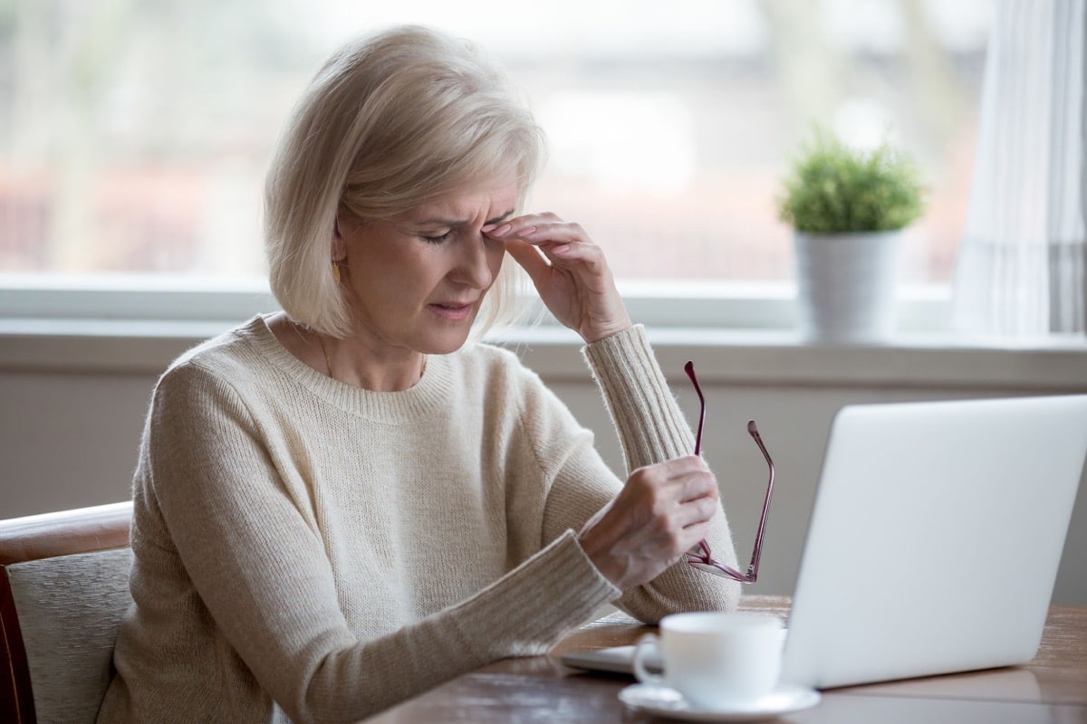 Upset fatigued mature business woman taking off glasses; workplace discrimination concept