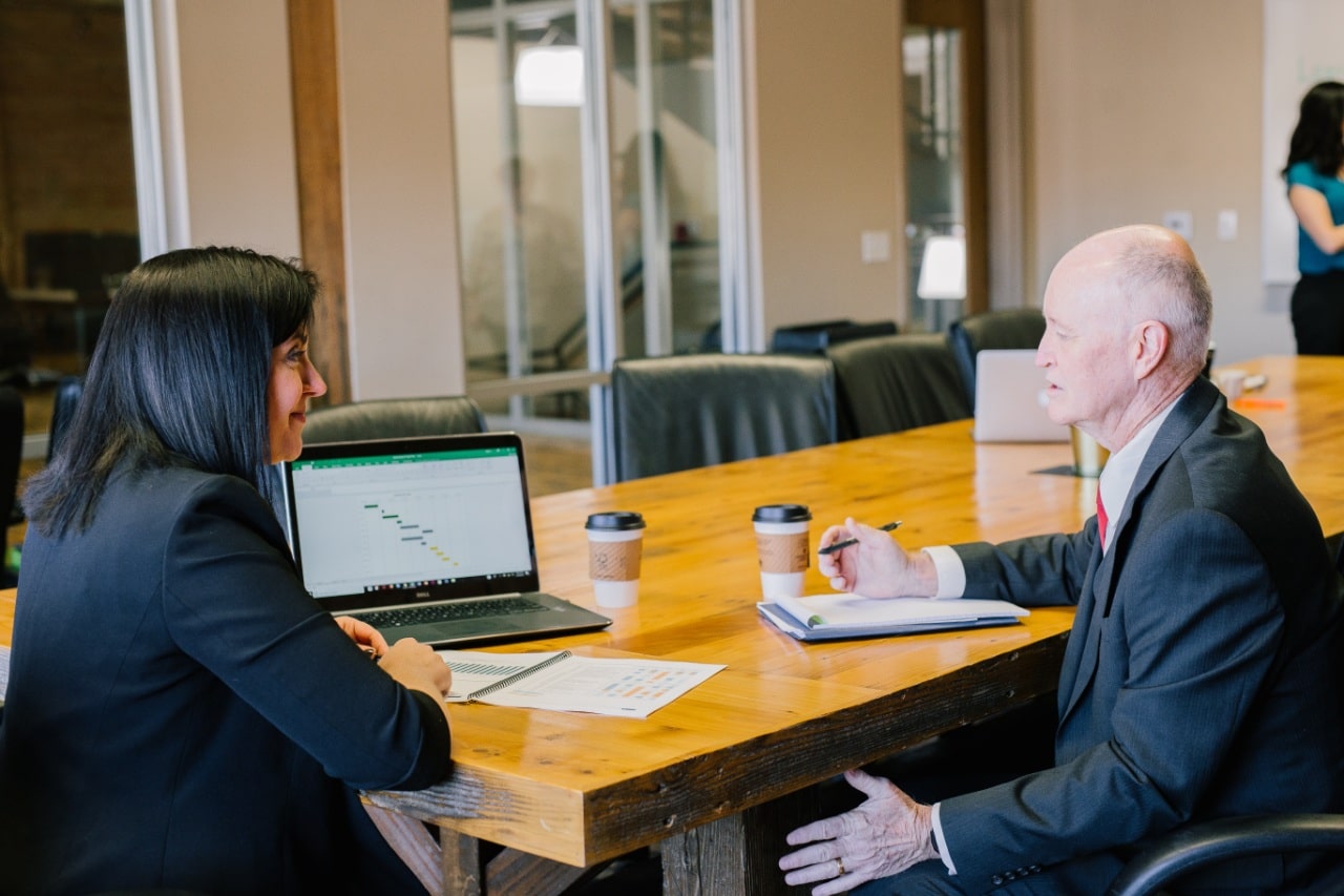 two coworkers chat in a boardroom; talent management insurance concept