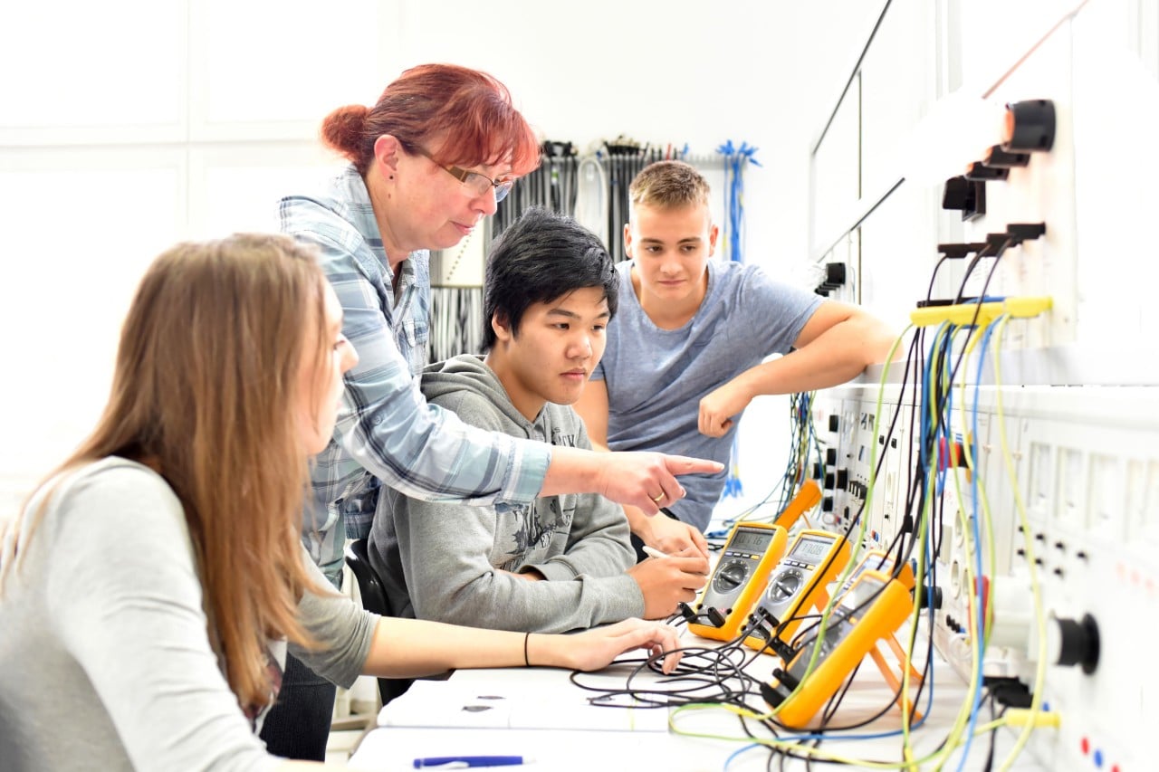 women demonstrates a voltmeter for. group of younger workers; state of talent management in manufacturing concept