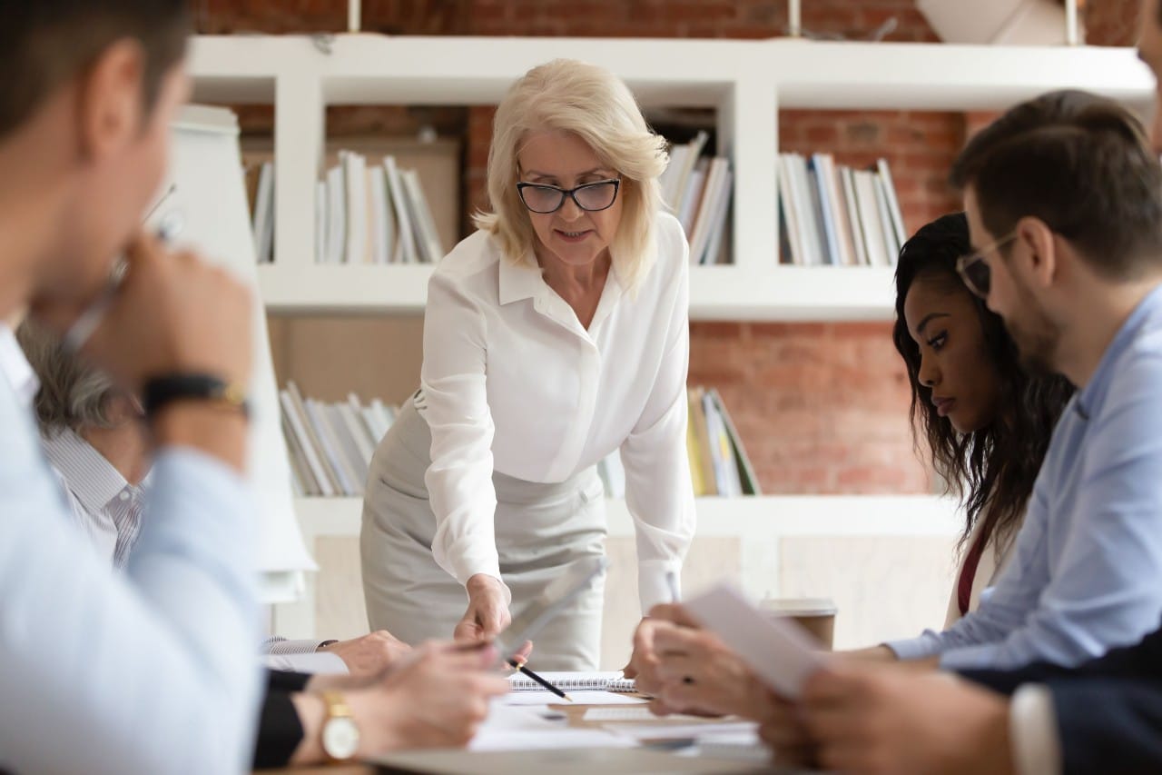 senior executive leads a meeting at a conference table; helping furloughed workers concept