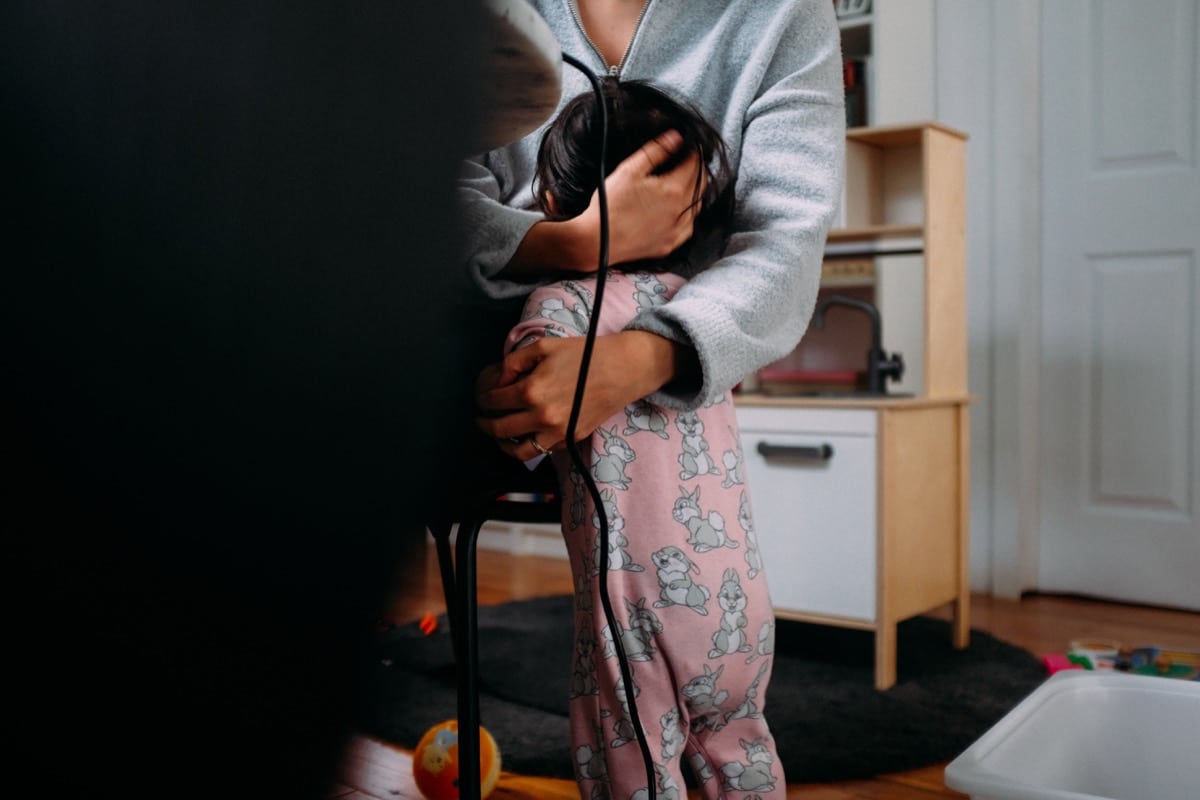 parent at desk in home office hugging a toddler; support remote employees concept