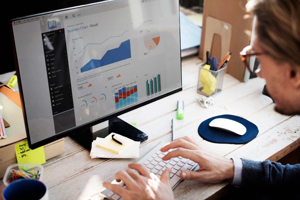 office worker at a desktop computer analyzes graphs and charts; human capital disclosure rule concept